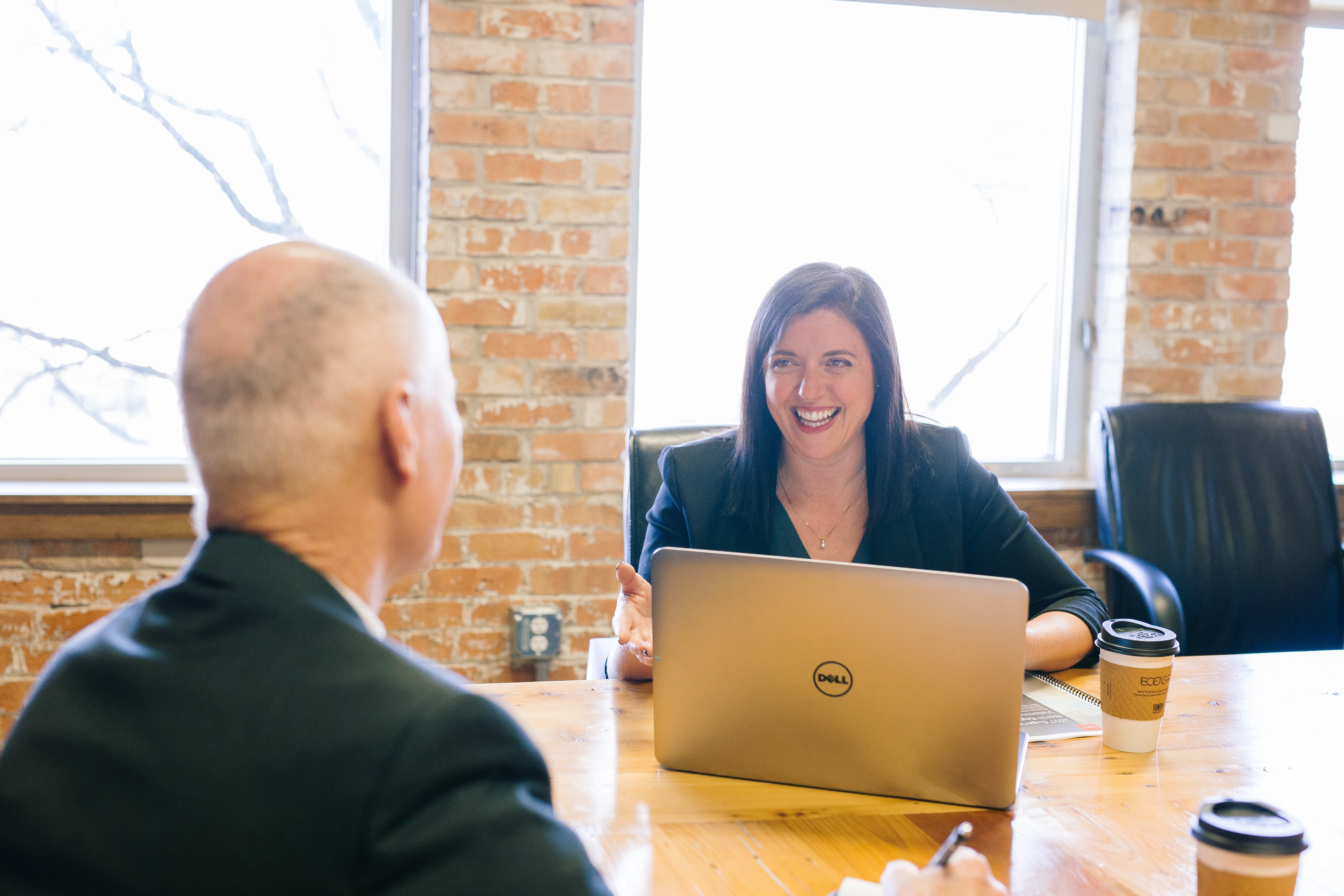 Woman with laptop smiles at man